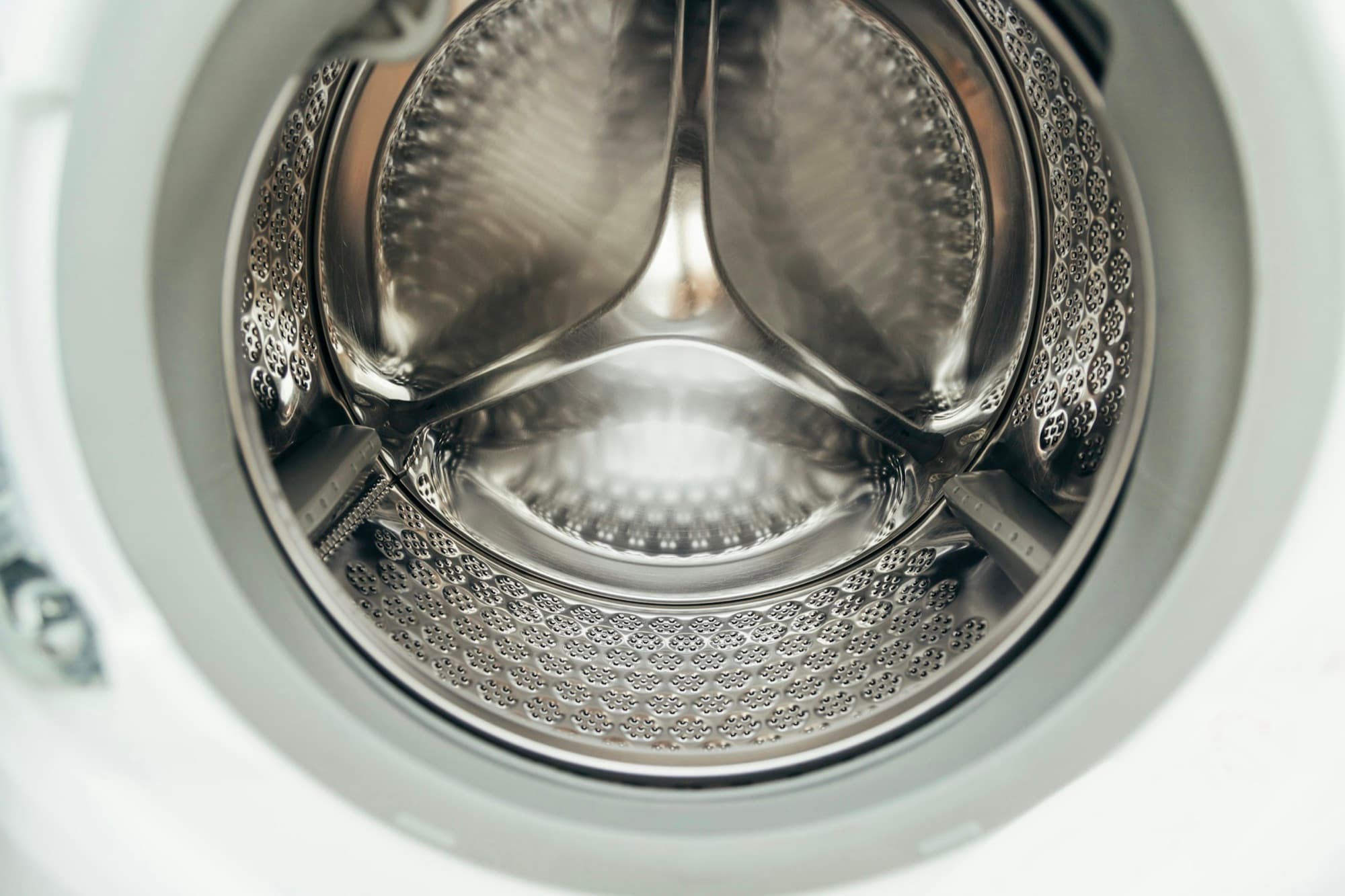 Inside a front-load washing machine: perforated stainless drum, formed lifters and rubber door gasket