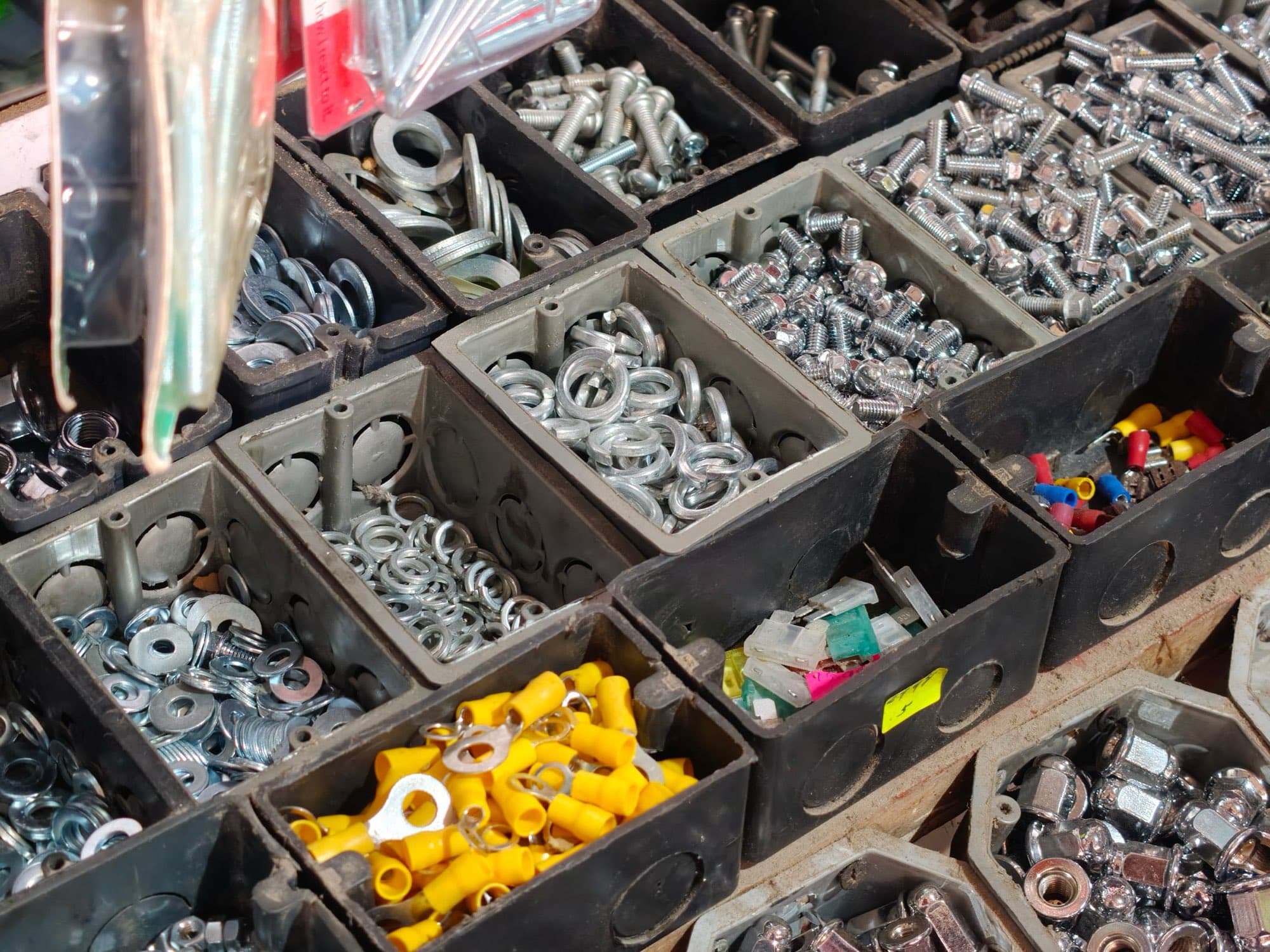 Bins of zinc-plated bolts, flat and split washers, cap nuts and crimp terminals sorted for sale