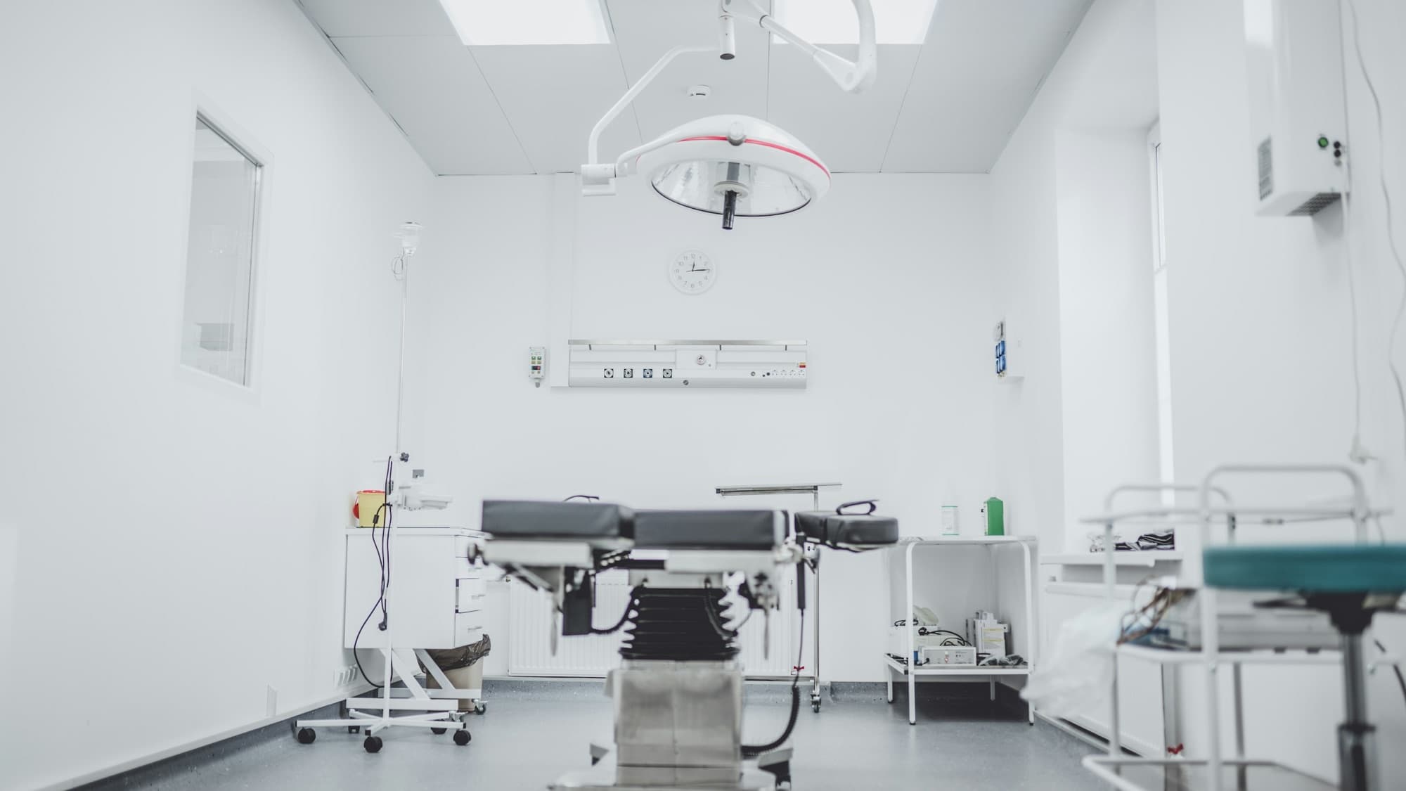 Empty operating room with articulated surgical light, adjustable operating table and instrument carts