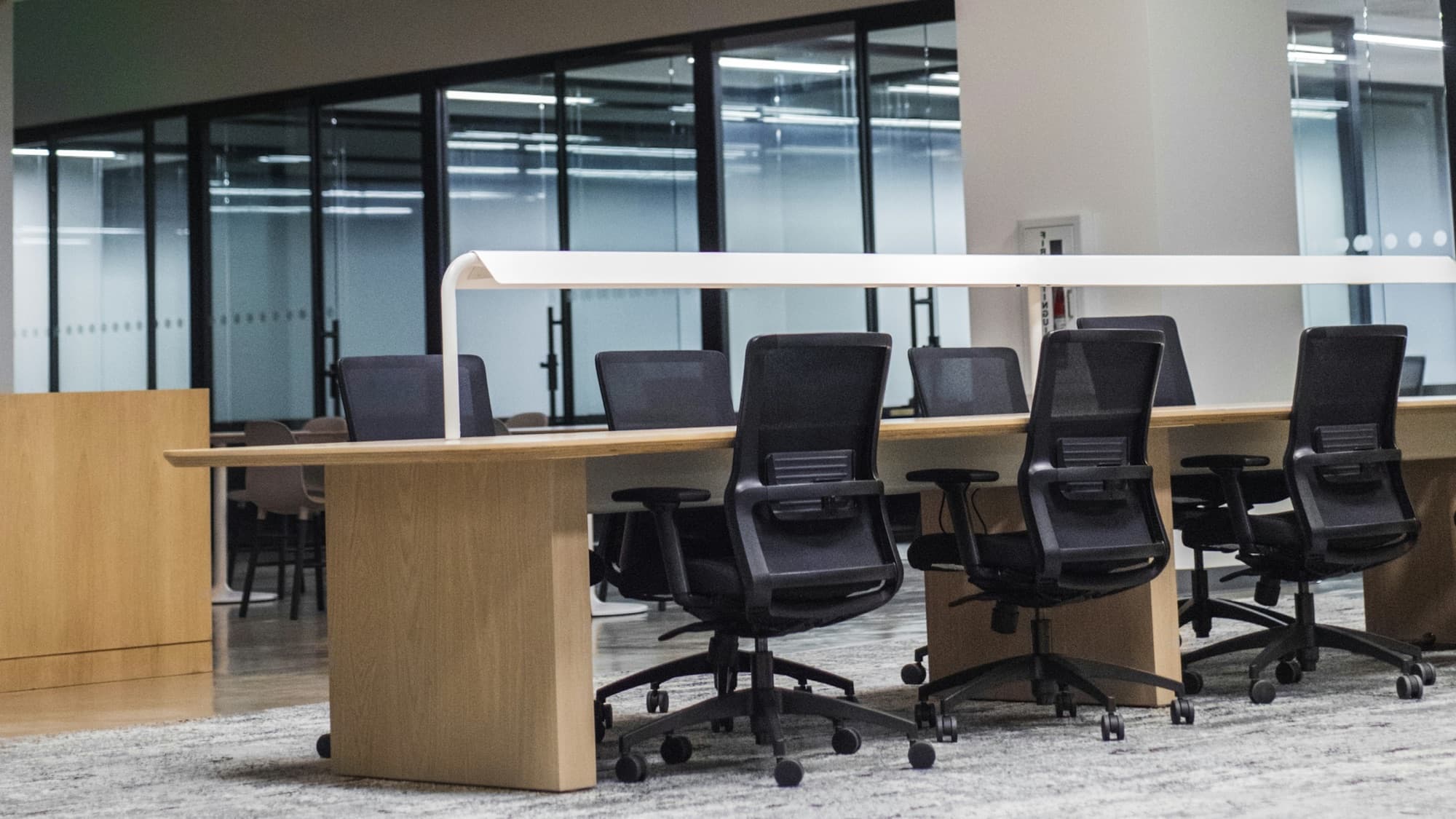 Row of mesh-back task chairs with adjustable arms and five-star bases at a shared office desk