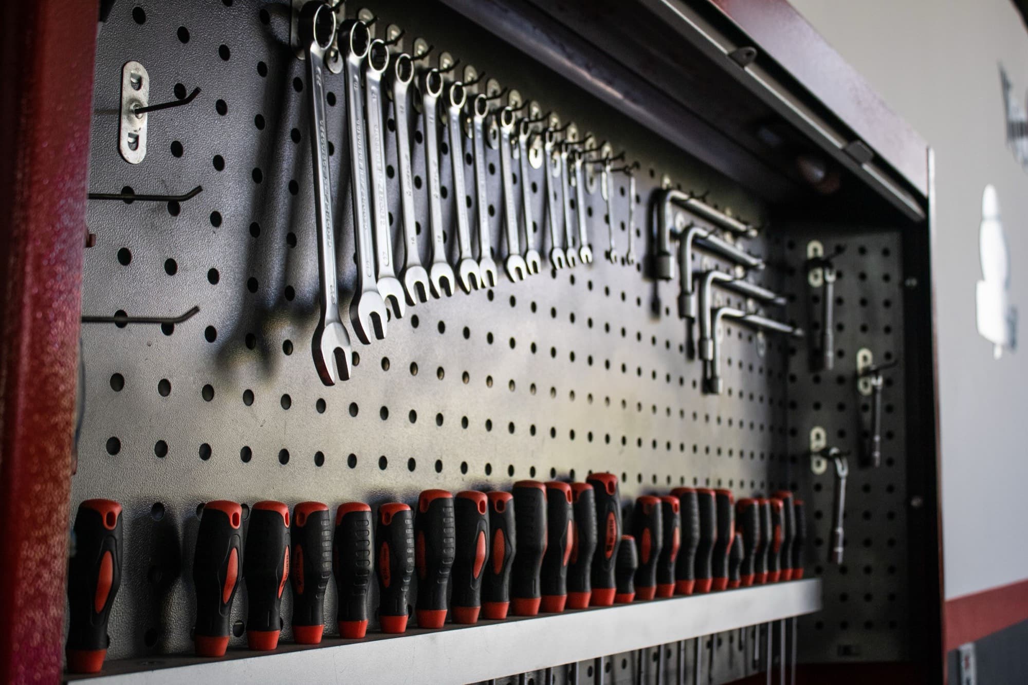 Pegboard tool wall with graduated combination wrenches, L-wrenches and a row of screwdrivers
