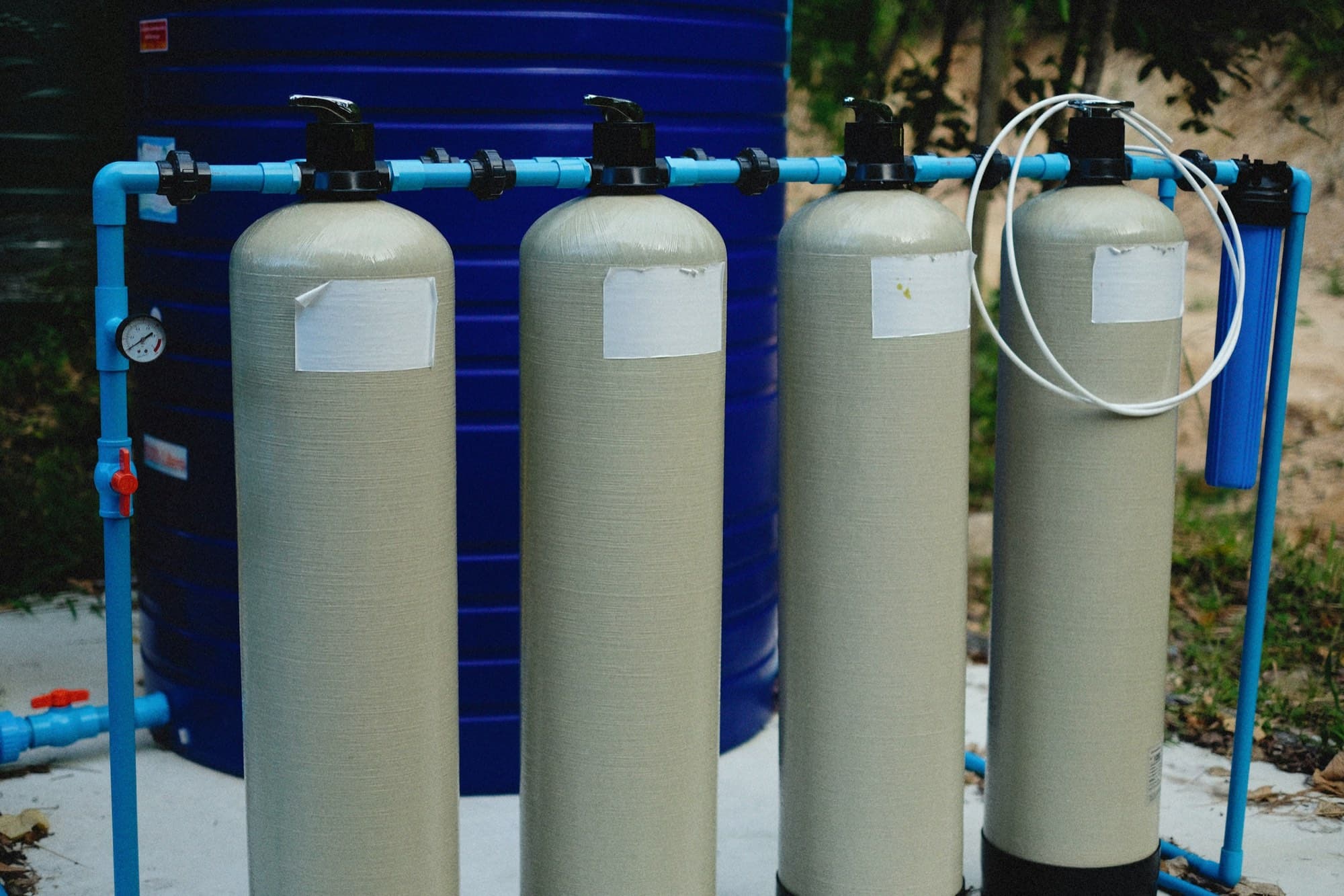 Water treatment system of fiberglass media tanks with control valves, PVC manifold and cartridge filter