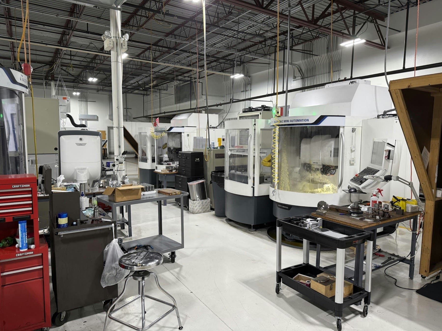 Precision job shop floor with enclosed CNC grinders, tool carts and inspection benches between machines
