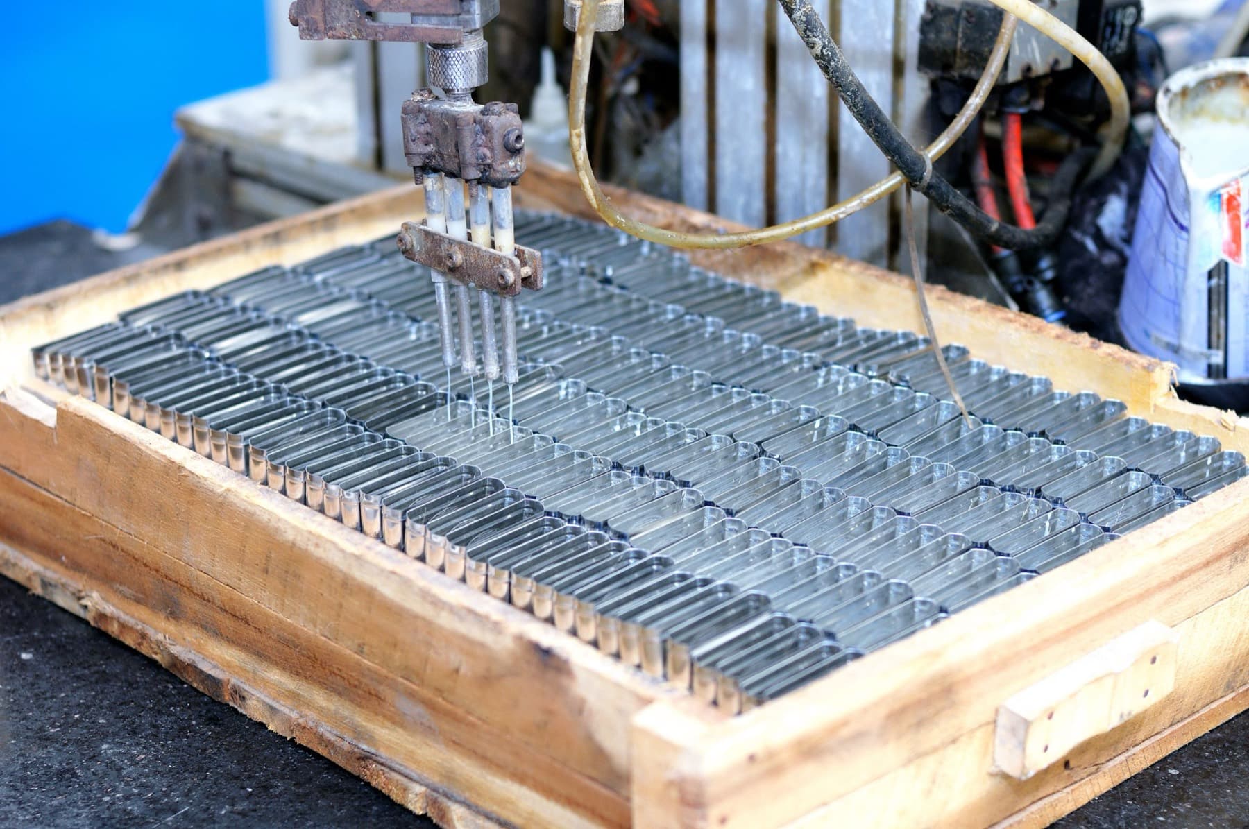 Multi-needle dispensing head working over a tray of formed metal ferrules