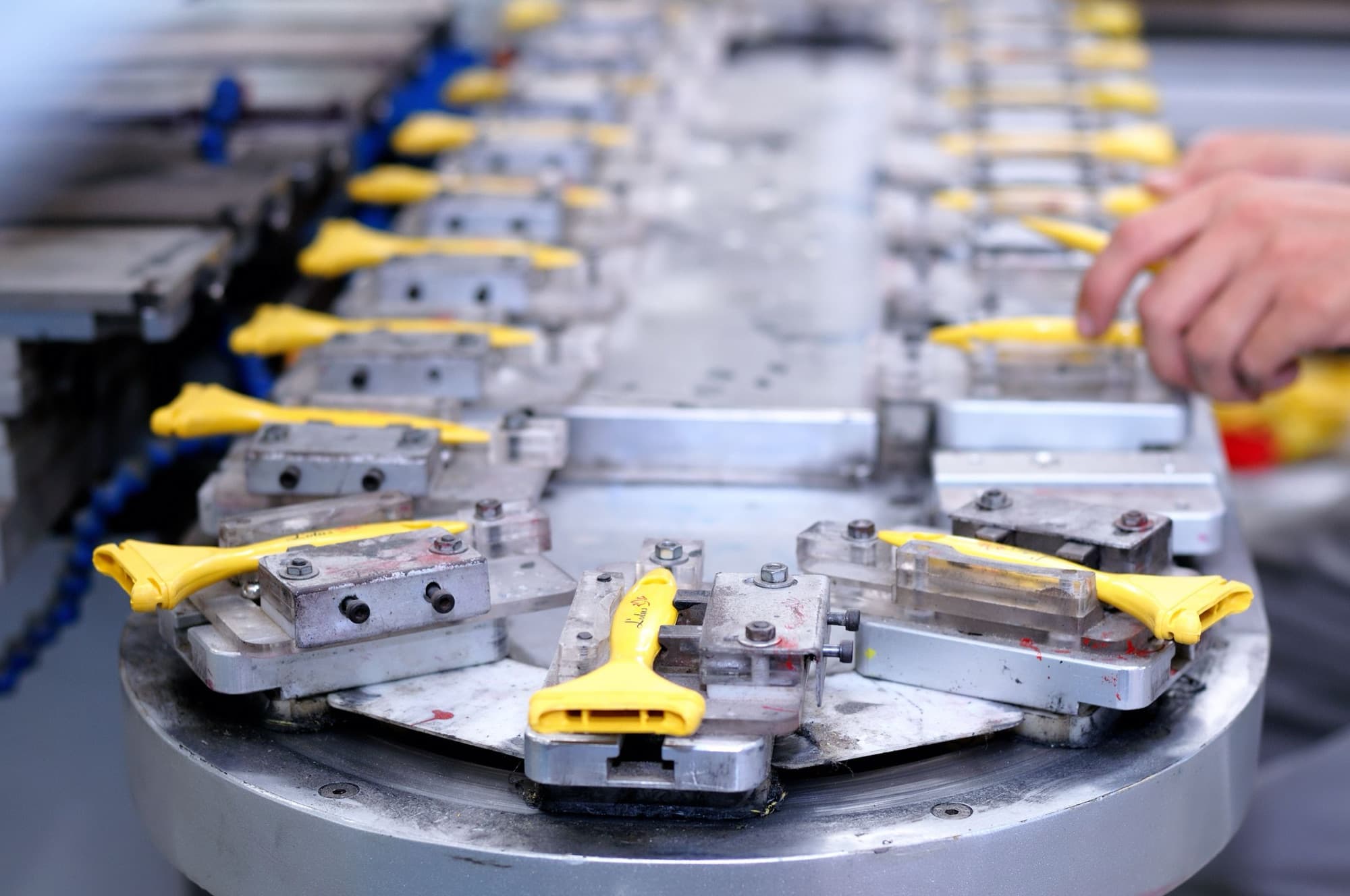 Molded plastic handles held in toggle-clamp fixtures on a rotary assembly table