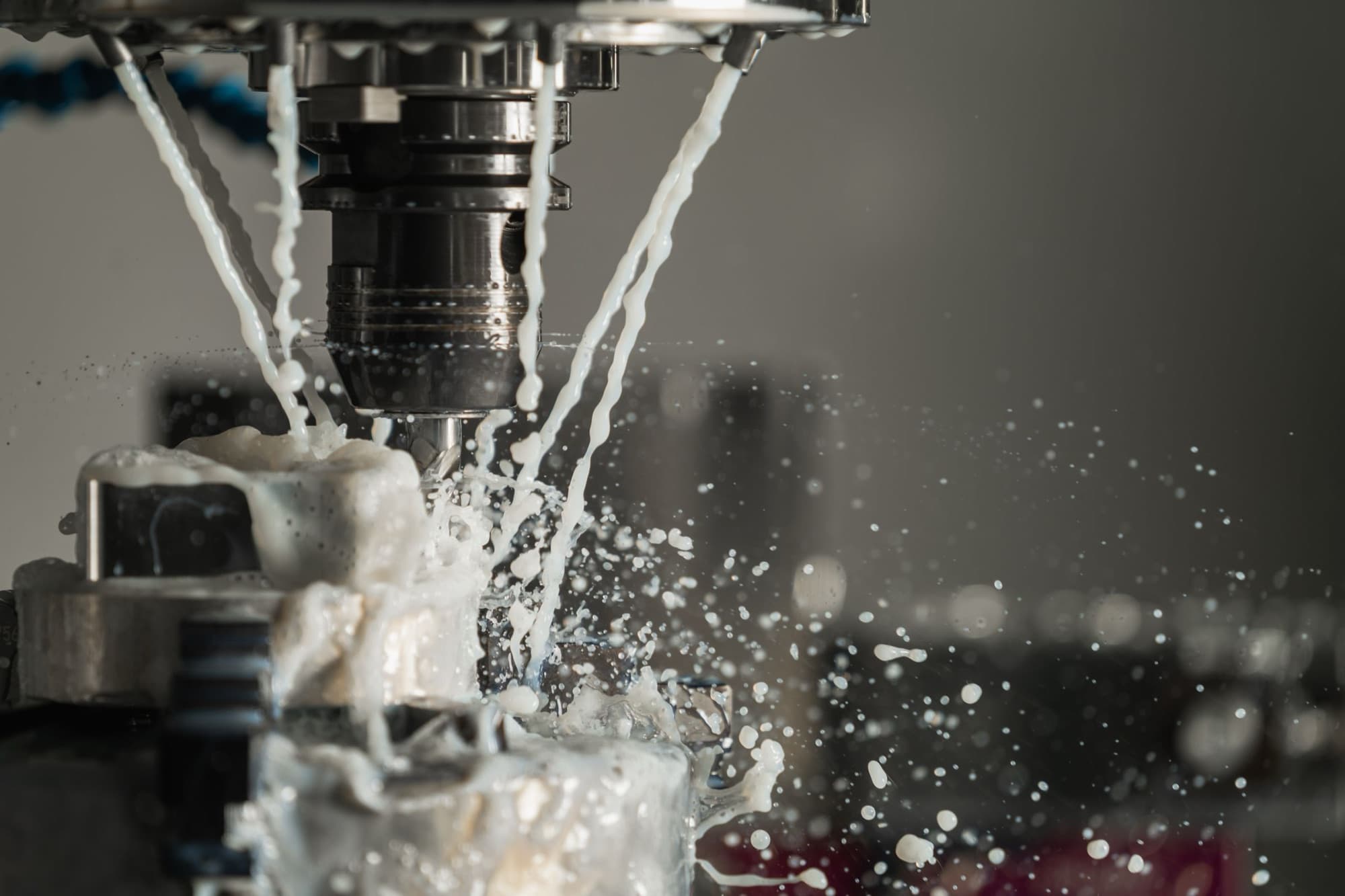 CNC milling spindle cutting a clamped metal workpiece under a flood of coolant