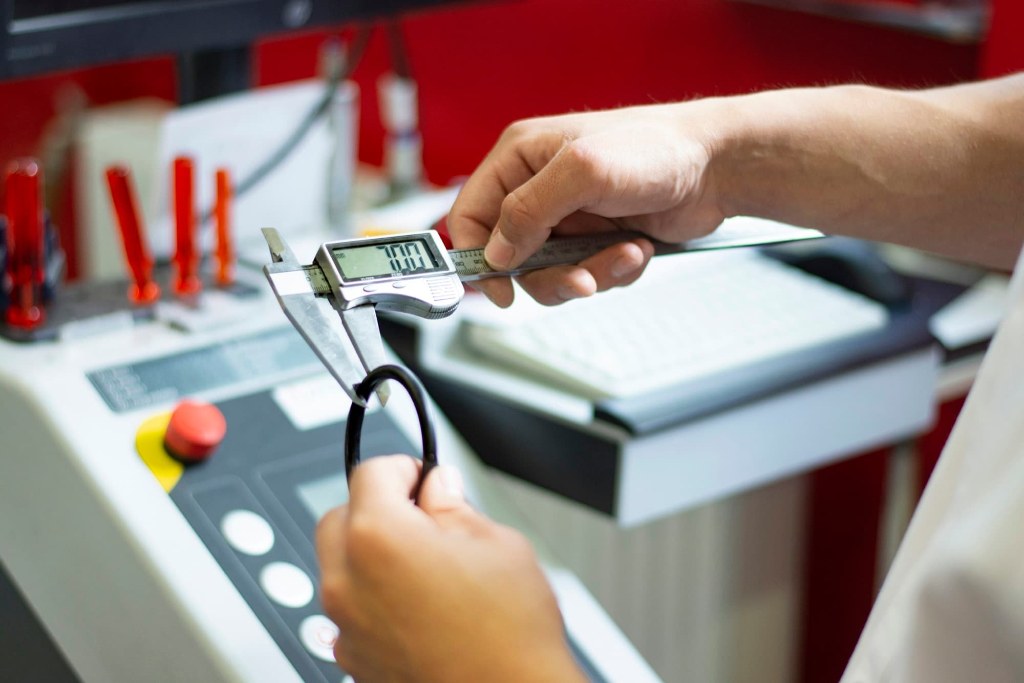 Inspector measures a molded rubber ring with a digital caliper at a production workstation