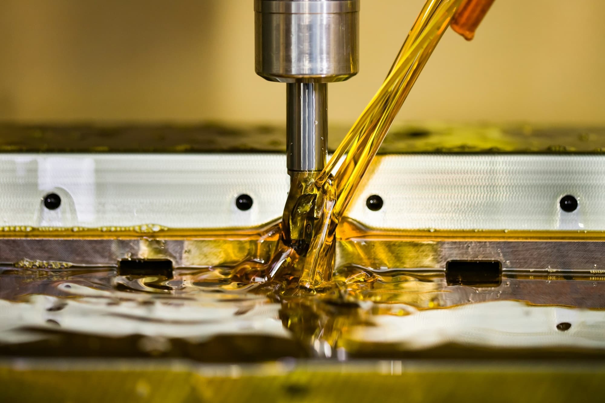 Carbide end mill cutting a pocket in a steel plate under a stream of cutting oil