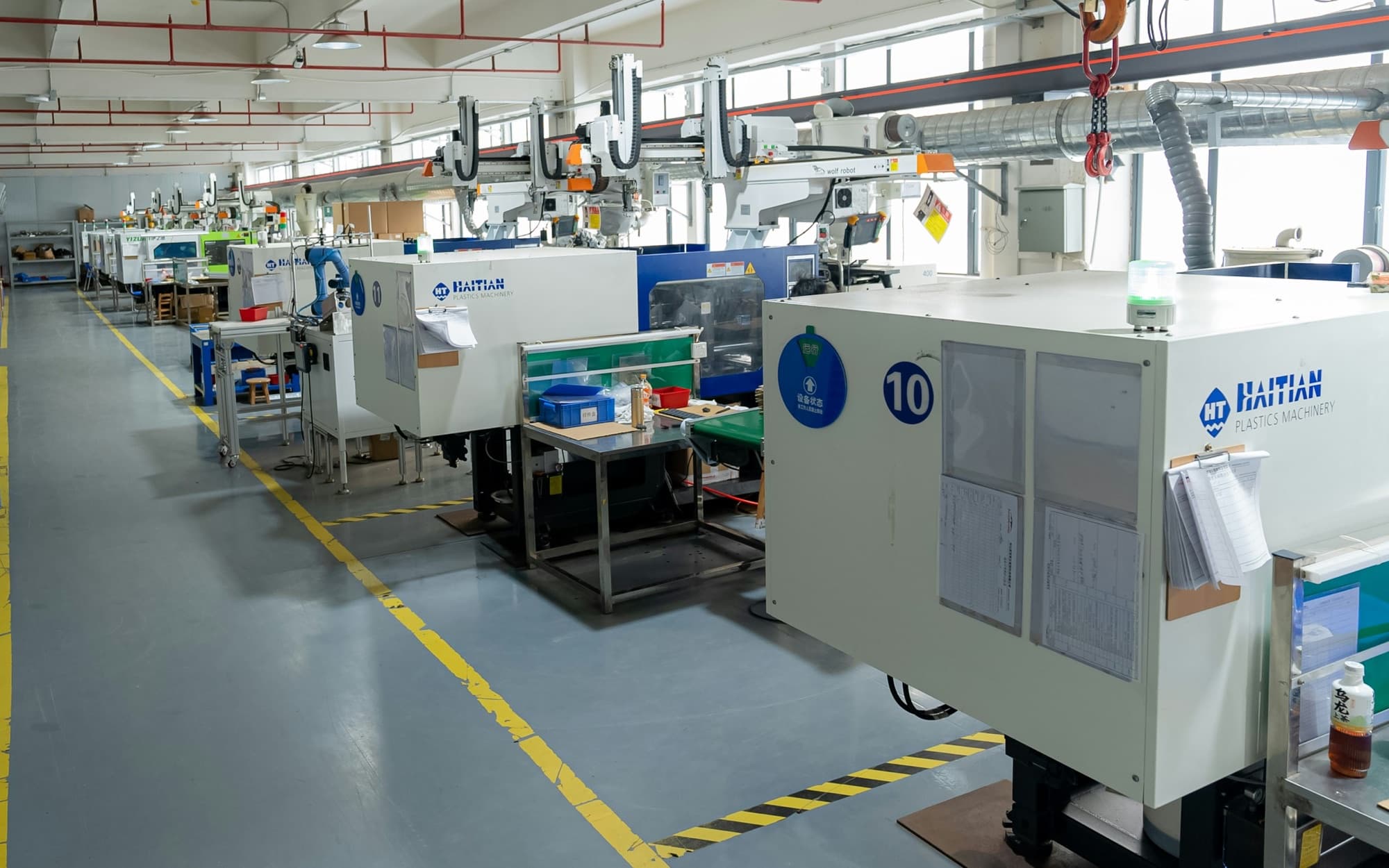 Line of injection molding presses with sprue pickers and a mold hoist on a clean molding floor