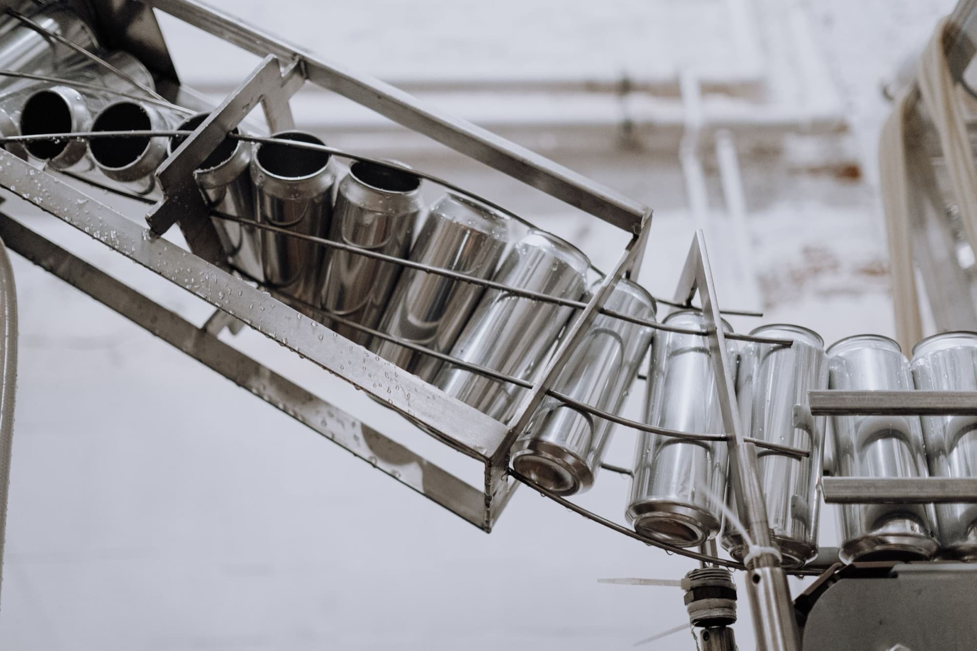 Seamless drawn aluminum can bodies riding a stainless conveyor chute on a production line