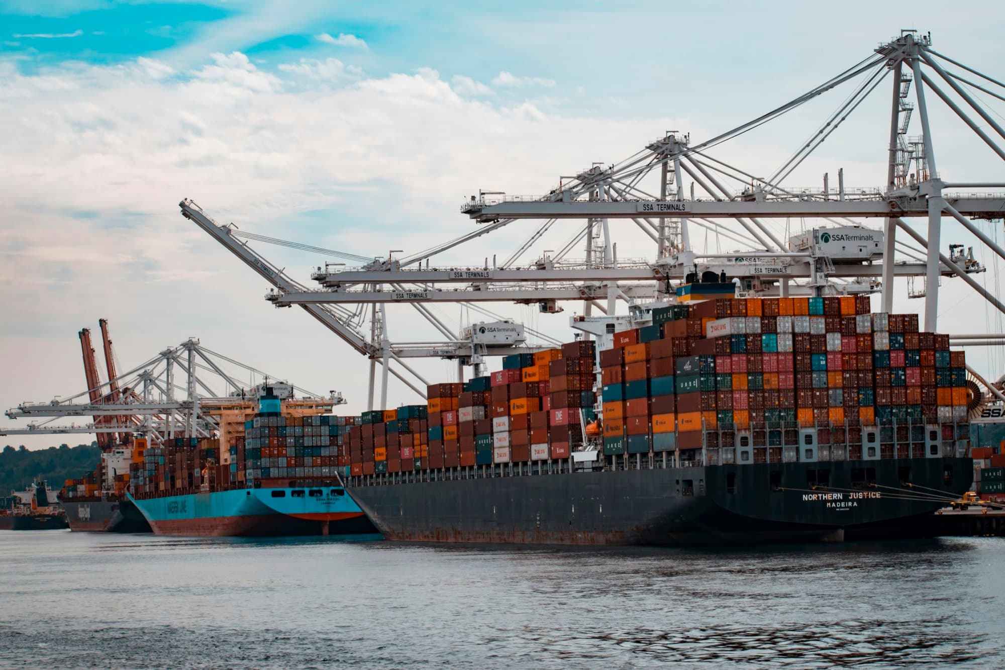 Fully loaded container ships berthed under ship-to-shore cranes at a busy cargo terminal