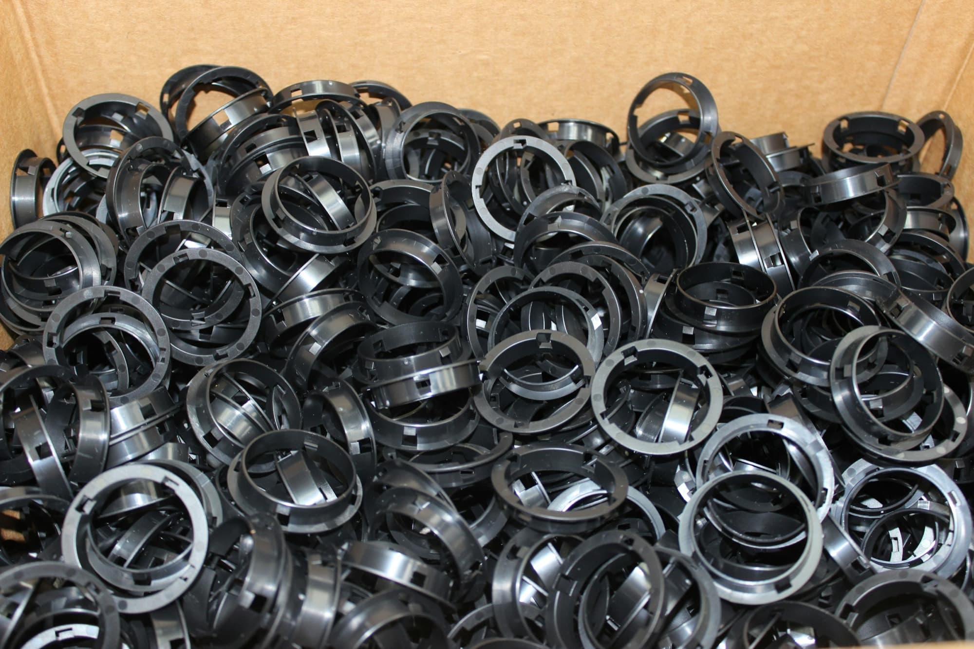 Carton filled with freshly injection molded black plastic retaining rings from a production run