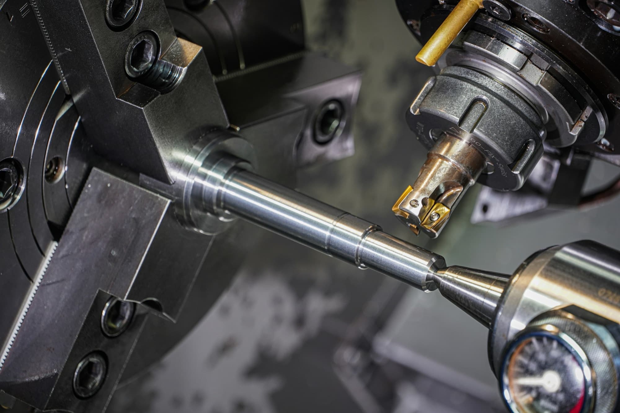 Turned steel shaft held between chuck and live center as a live tool machines it