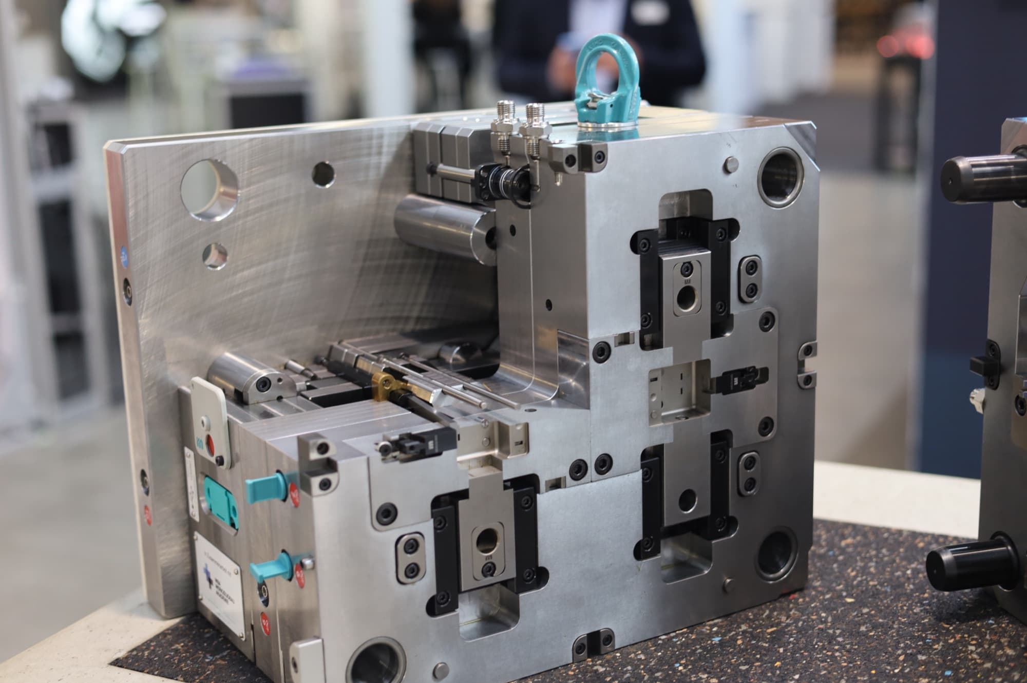Steel injection mold tool with side-action slides, cooling fittings and a lifting eye on a bench