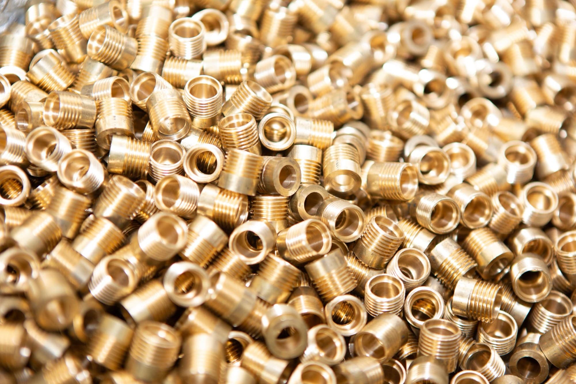 Bulk batch of freshly turned brass threaded fittings from a production run