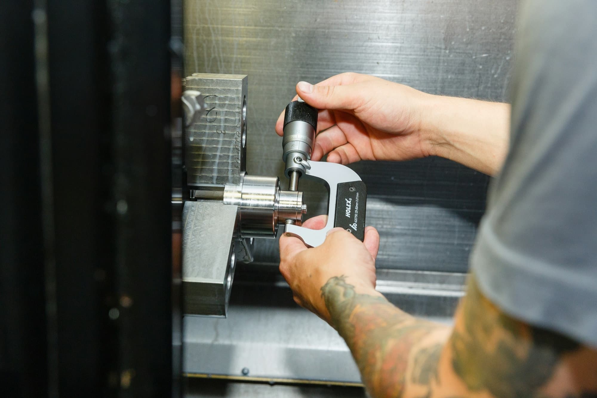 Machinist checks a turned steel part with an outside micrometer while it is still fixtured