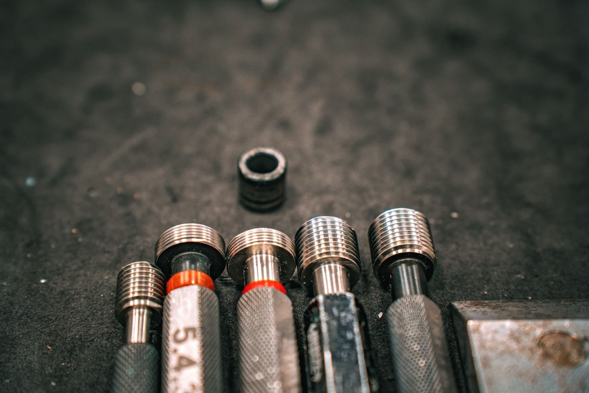 Go/no-go thread plug gauges and a thread ring gauge laid out on a workbench